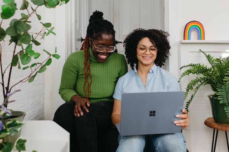 Two people collaborating while looking at a laptop
